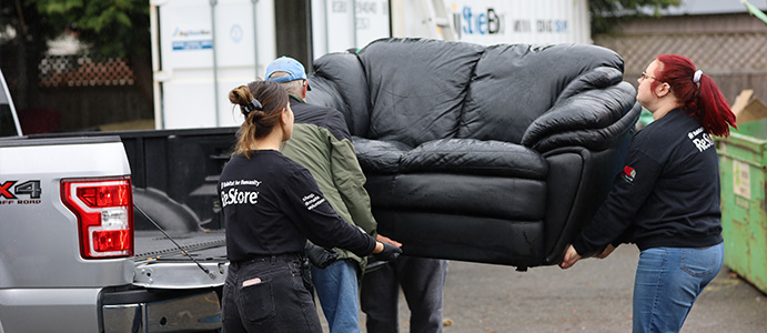Habitat team members moving a couch