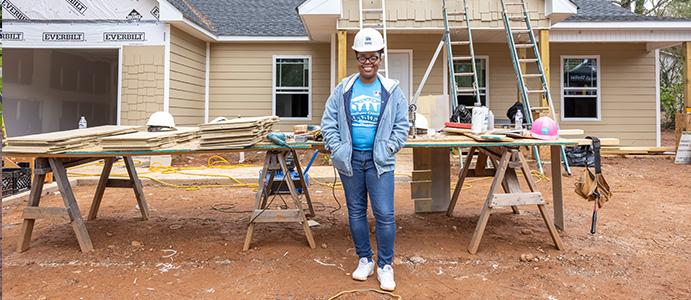 Habitat team member standing in front of a home